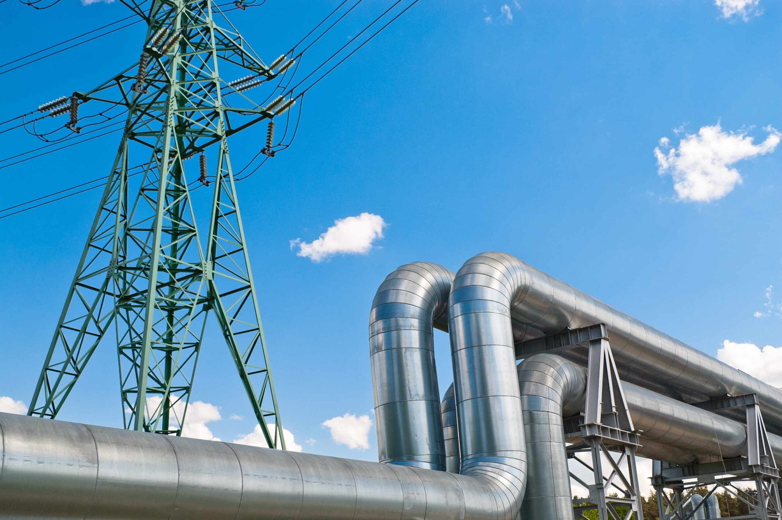pipeline and power line against blue sky with clouds.